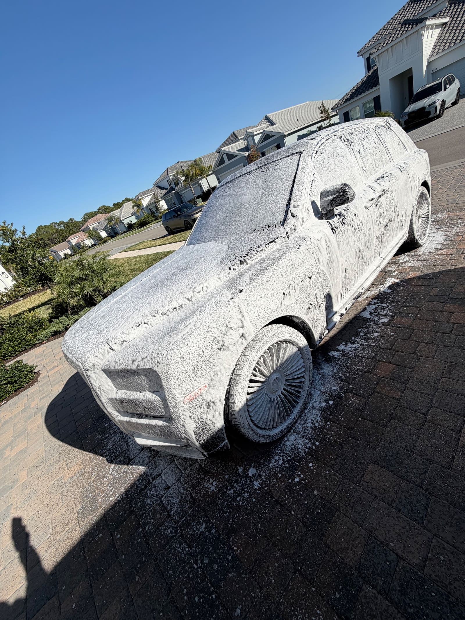 A full-size SUV covered in thick foam during a Flawless Finish wash